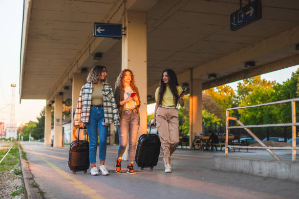 istock Three beautiful young women walking at a train station while dragging their suitcases and holding their passports and tickets during sunset 1366147794