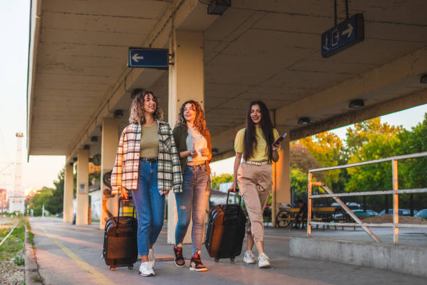 istock Three beautiful young women walking at a train station while dragging their suitcases and holding their passports and tickets during sunset 1366147799
