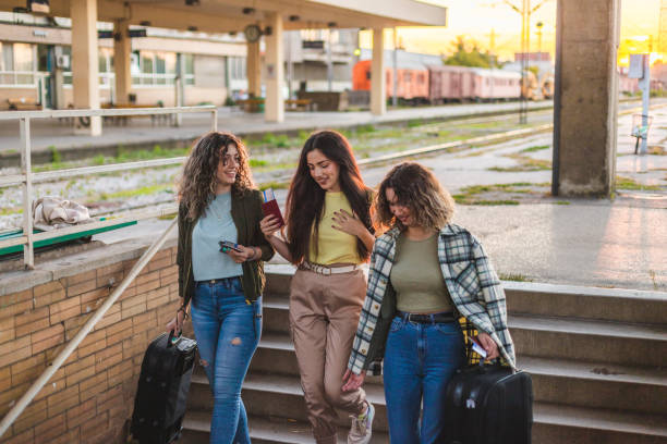 istock Three young female friends walking down the stairs at a train station while holding their suitcases 1366147807