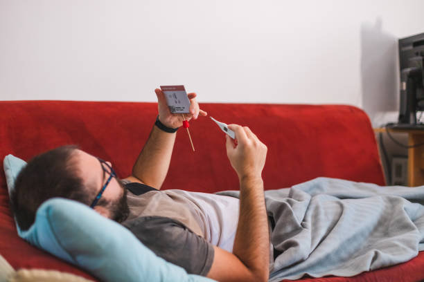 istock Ill young man holding a COVID-19 rapid self-test kit showing that he is Coronavirus positive while laying in bed at home 1366147961