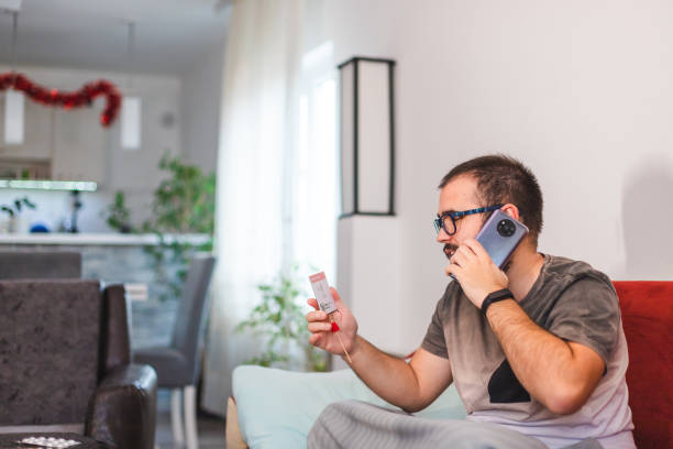 istock Happy young man talking on his mobile smart phone showing his negative COVID-19 self-test kit while being sick at home 1366148532
