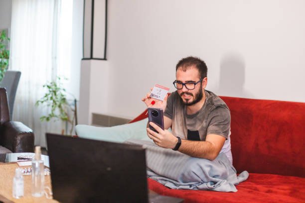 istock Happy young man talking on his mobile smart phone showing his negative COVID-19 self-test kit while being sick at home 1366148553