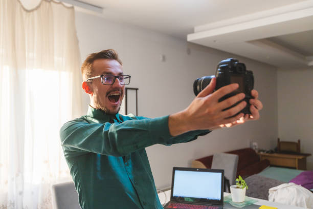 istock Young white male with glasses vlogging with a professional DSLR camera while making a surprised face to the camera 1366150815