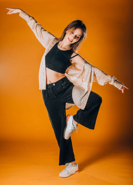istock Young dancer doing acrobat moves isolated on orange wall 1366153649