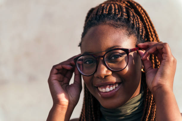 istock smiling young black woman putting on her glasses 1366158155