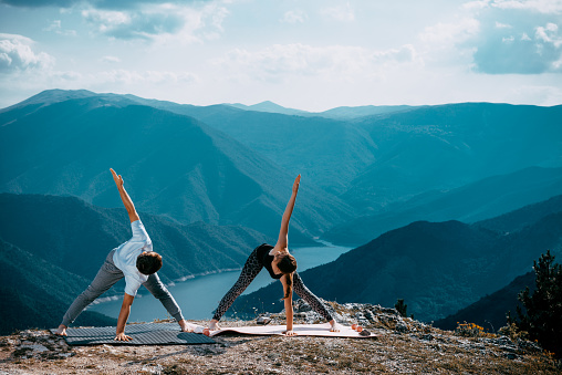 Yoga practice exercise class concept. Young man doing exercises. Young woman and man practicing yoga at mountain