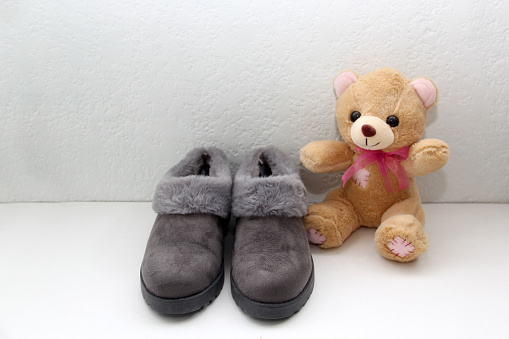 gray slippers ready to rest and go to bed next to a teddy bear to relax and unwind