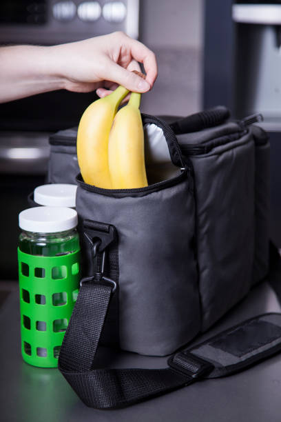 Placing bananas in a large insulated food bag or lunch bag box stock photo