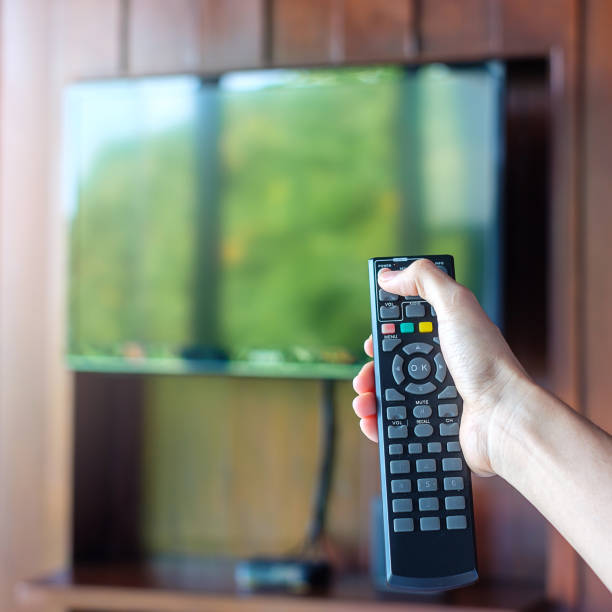 istock hand using remote controller for adjust Smart TV inside the modern room at home or luxury hotel 1366183597