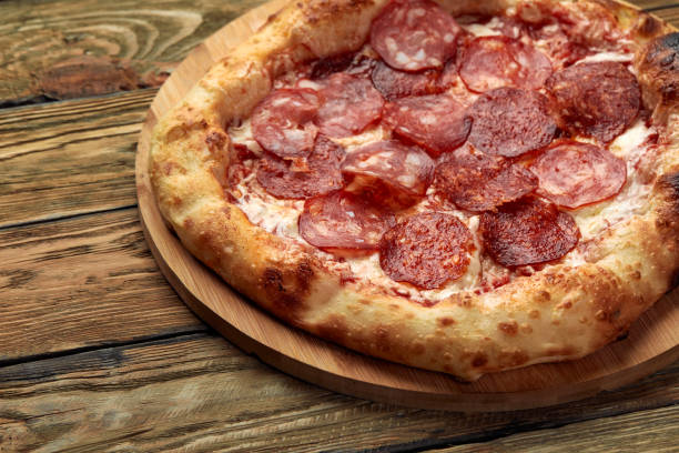 istock Pepperoni pizza on rustic, vintage style wood background. Top view 1366183804