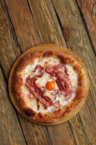 istock Carbonara pizza with bacon and egg on wooden background 1366184514