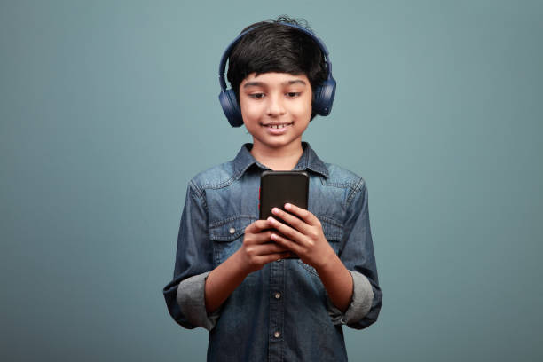 istock Smiling boy wearing a headset looking at a smart phone in hand 1366188454
