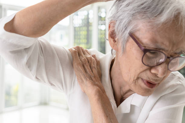 anziana donna anziana asiatica con dolore alle ossa della spalla, rigidità e dolore quando si solleva il braccio, soffre di difficoltà nel sollevare o allungare il braccio da una spalla congelata, infiammazione della spalla - shoulder bone foto e immagini stock