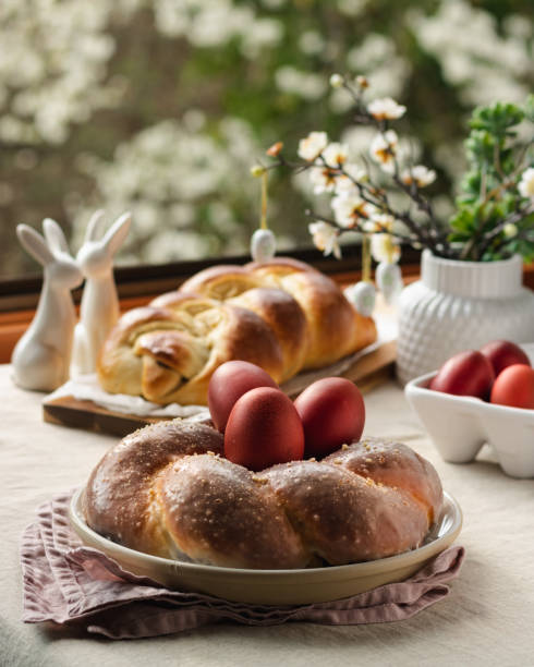 easter traditional bread, austrian ostern zopf, greek tsoureki and red eggs on a table with linen tablecloth with spring window view, still life - ostern stok fotoğraflar ve resimler