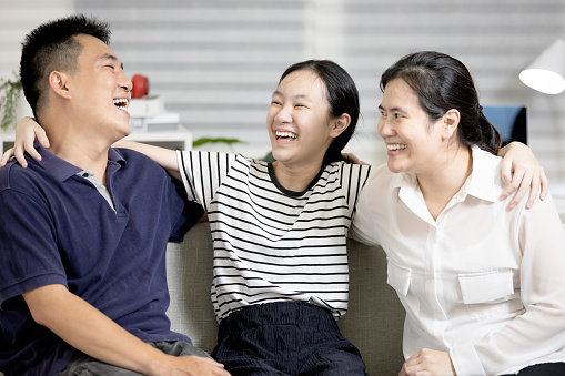 Happy parent and teenager,father mother and daughter have fun enjoy free time on weekend,asian family laughing playing together sitting on couch in living room,lifestyle,moment of warmth and happiness