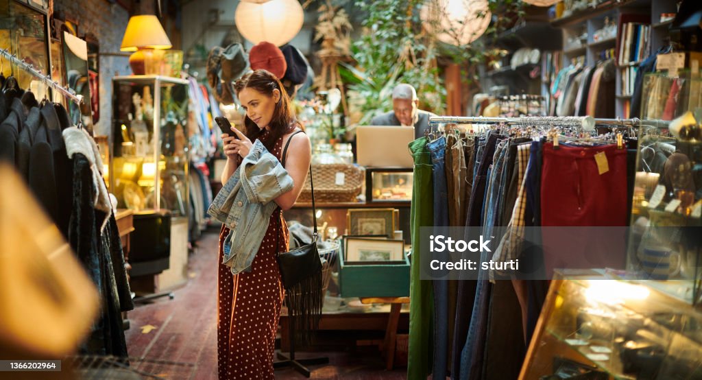 second hand clothes shop snapping a bargain in vintage shop Retail Stock Photo