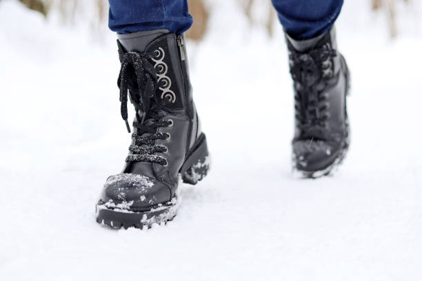 istock Female legs in black leather lace-up boots on a snow 1366203237