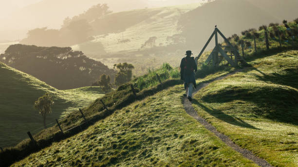 un mochilero caminando por la pista de la granja en las verdes colinas. tomada en la pista de playa de wharariki, golden bay, isla sur. - golden bay fotografías e imágenes de stock