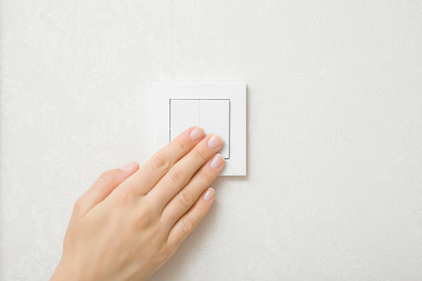 mujer adulta joven presionando a mano los botones del interruptor de luz de plástico blanco en la pared de la habitación. encienda o apague la iluminación. closeup. ahorro energético en casa. - pushing women wall people fotografías e imágenes de stock