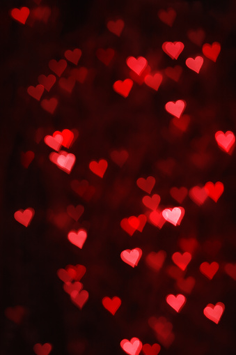 Valentine's Day. background from red hearts. bokeh. black background and many hearts