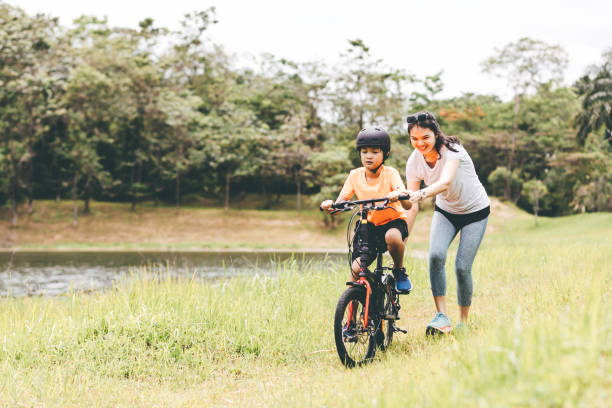 madre che insegna al figlio ad andare in bicicletta - cycling teenager action sport foto e immagini stock