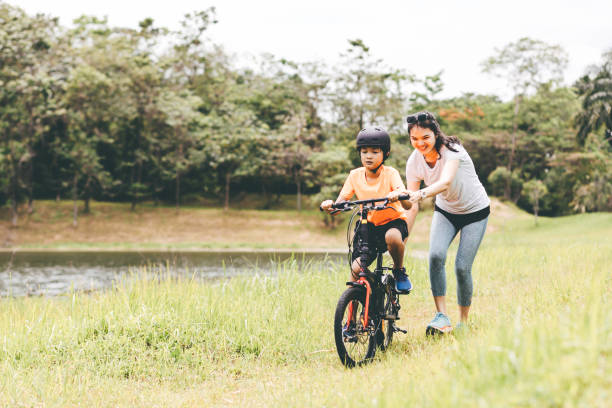 mother teaching son to ride a bicycle - cycling teenager action sport imagens e fotografias de stock