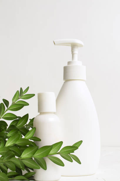 istock White plastic bottles with dispenser close-up with green leaves on a white background. Blank label for branding mock-up. Natural beauty product concept. Shower gel, soap, cream, shampoo 1366213159