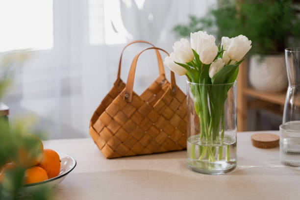 istock straw basket and white tulips on table with linen tablecloth in modern bright interior. Sunny light. Spring decoration. cozy festive home. 1366219907