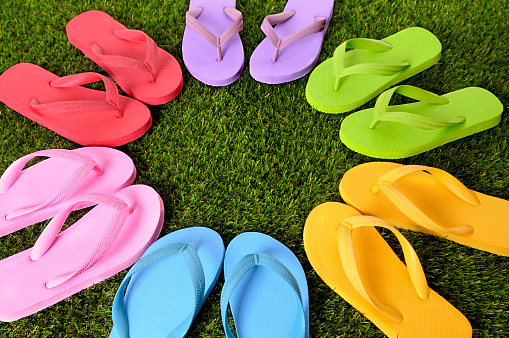 Multicolor circle of flip flops on grass.