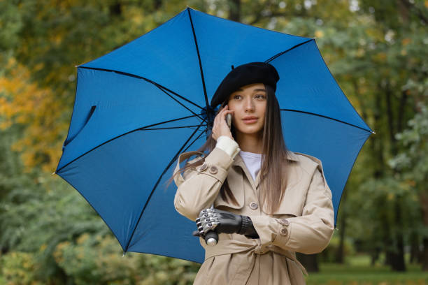 istock cyber woman under an umbrella with a bionic prosthesis on her arm is talking on the phone and waving to her friends 1366221644