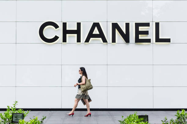 woman shopping in front of a chanel fashion boutique with the logo on the wall. - lifestyles designer store luxury imagens e fotografias de stock