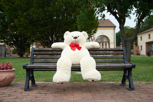 istock big polar plush bear with red tie, sits on a bench 1366225455