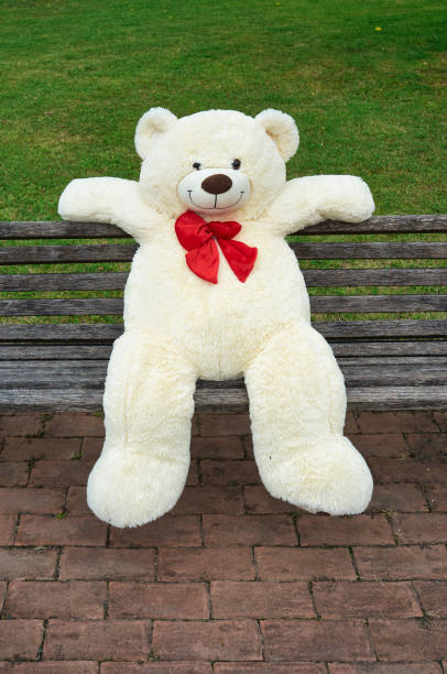 istock big polar plush bear with red tie, sits on a bench 1366225457