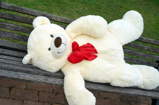 istock big polar plush bear with red tie, lying on the a bench 1366225463