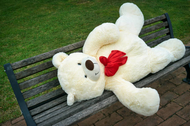 istock big polar plush bear with red tie, lying on the a bench 1366225467