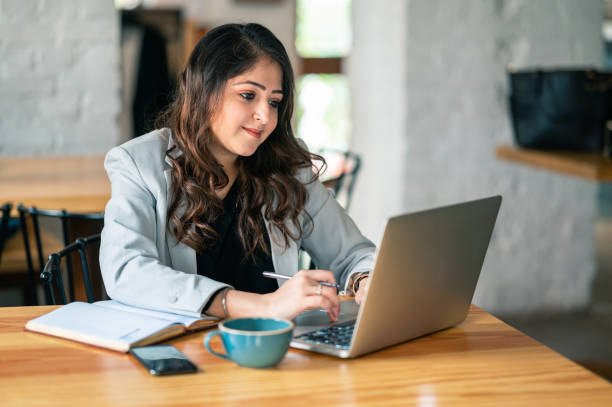 Young woman working on laptop and typing important data Indoor image of young Businesswoman working on laptop and typing important data while sitting in a cafe. Freelance Writing Jobs stock pictures, royalty-free photos & images