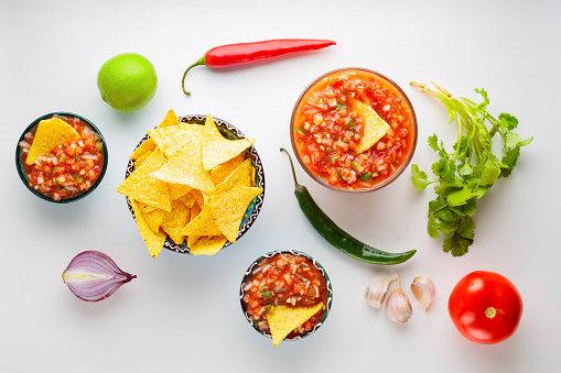 Salsa sauce and ingredients. Mexican homemade salsa sauce and nacho chips on a white background. Food background. Top view