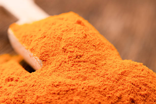 Ground turmeric in a wooden scoop close up