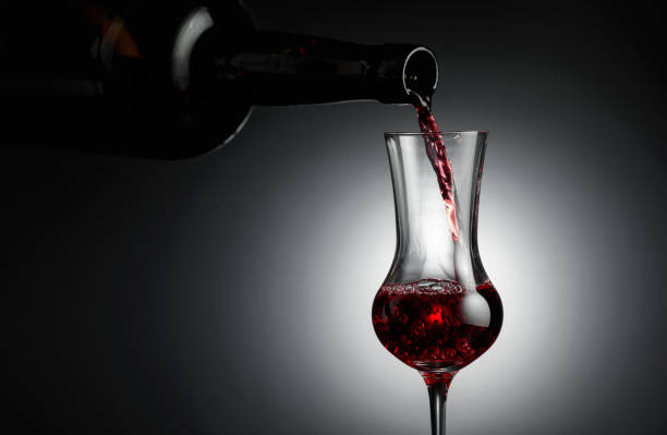 dessert wine or liqueur is poured into a glass from an ancient bottle. - action alcohol alcoholism bar imagens e fotografias de stock