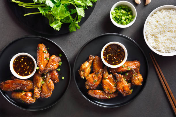 Honey-soy chicken wings Sticky honey-soy chicken wings over dark stone background. Top view, flat lay teriyaki stock pictures, royalty-free photos & images