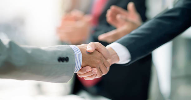due uomini d'affari stringono la mano per il lavoro di squadra di fusione e acquisizione aziendale in ufficio. - incorporazioni e acqusizioni foto e immagini stock