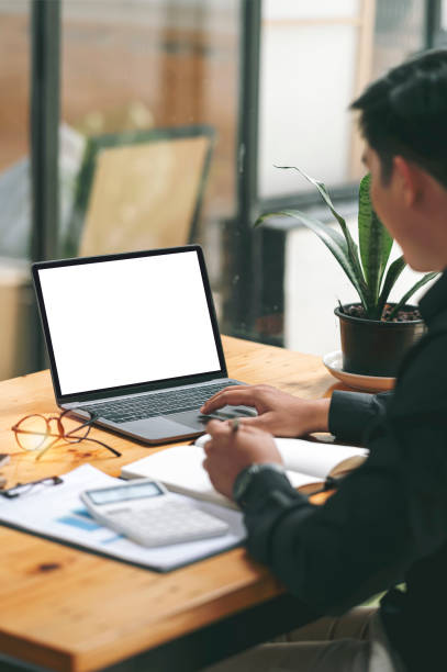 makieta przedstawiająca mężczyznę korzystającego z laptopa z pustym ekranem na drewnianym stole. - wireless technology working at home one person reading zdjęcia i obrazy z banku zdjęć