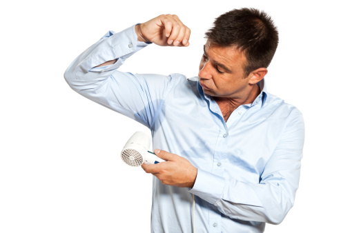 one caucasian man with sweat stain perspire drying shirt with hair dryer in studio    on white background