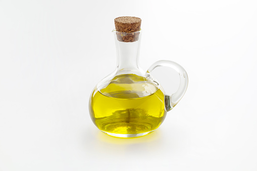 Olive oil in vintage glass bottle on white background