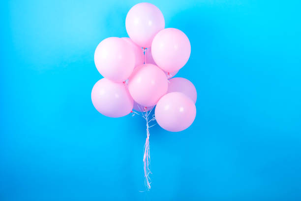 Pink birthday balloons on blue (cyan) background with copy space for text. Pink pastel party balloons, free space. Love, happiness, valentine, wedding honeymoon concept. Happy holiday flying balloons stock photo