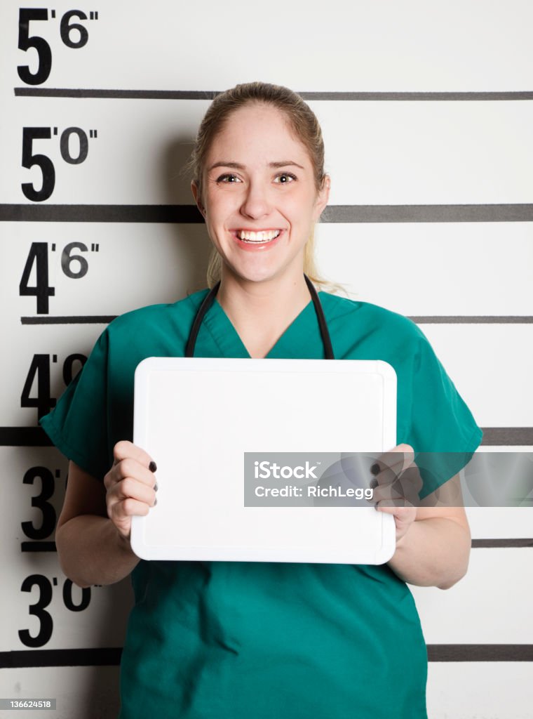 Mugshot of a Healthcare Worker A mugshot/booking photo of a young woman wearing medical scrubs. Prison Stock Photo