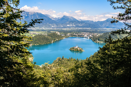 View of Lake Bled in Slovenia from the viewpoint on the hill above the town. In the distance you can see the high rocky mountains of the Julian Alps.