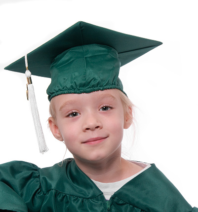 A head and shoulders portrait of a preschool graduate wearing her cap and gown.