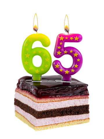 Appetizing birthday cake with burning candles for 65th anniversary isolated on white background