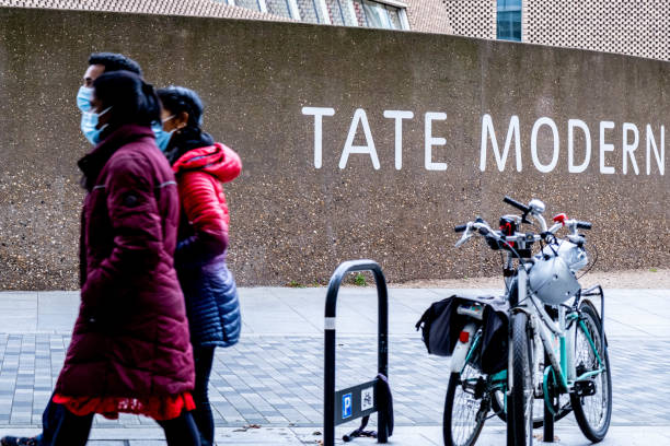 small family group of people wearing protective face masks walking past a tate modern sign - group of people art museum clothing lifestyles imagens e fotografias de stock